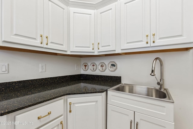 kitchen featuring white cabinets, dark stone countertops, and sink