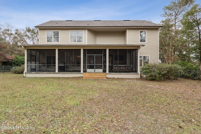 rear view of house featuring a lawn and a sunroom