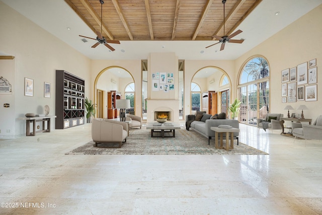 unfurnished living room with beamed ceiling, ceiling fan, wooden ceiling, and a high ceiling