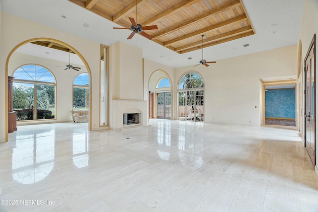 unfurnished living room featuring a large fireplace, beam ceiling, wood ceiling, and a towering ceiling