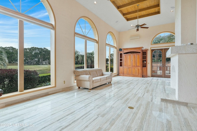 unfurnished living room with a towering ceiling, light wood-type flooring, wood ceiling, ceiling fan, and beam ceiling