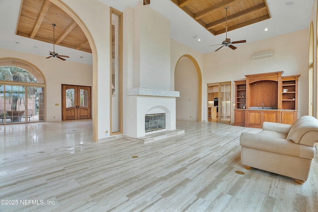 living room featuring beam ceiling, a fireplace, wood ceiling, and a high ceiling