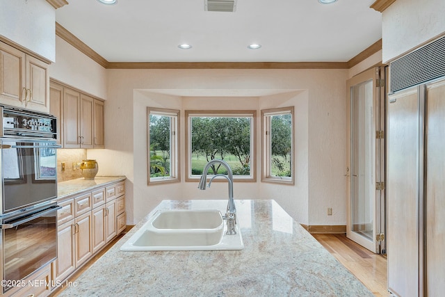 kitchen featuring built in fridge, light brown cabinets, ornamental molding, and sink