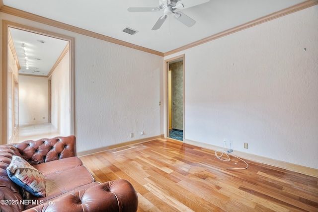 sitting room with hardwood / wood-style flooring, ceiling fan, and crown molding