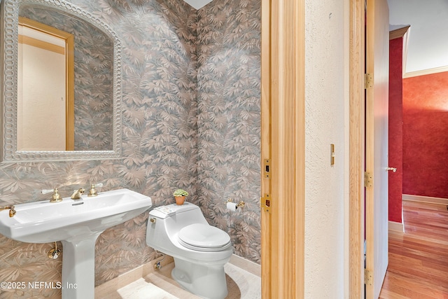 bathroom featuring hardwood / wood-style flooring, toilet, and ornamental molding