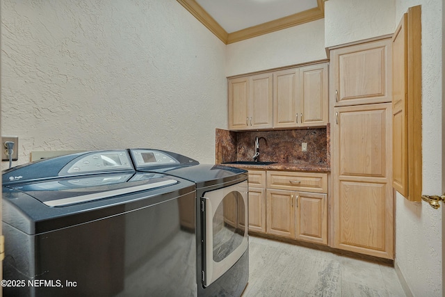 washroom with sink, cabinets, independent washer and dryer, and ornamental molding