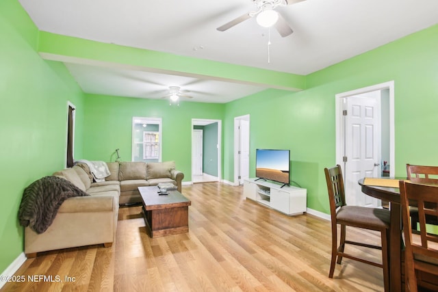 living room featuring ceiling fan, light wood-type flooring, and beam ceiling