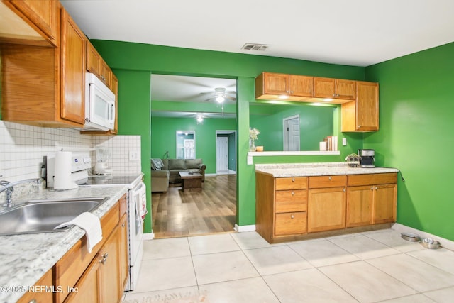 kitchen featuring sink, white appliances, ceiling fan, light tile patterned floors, and backsplash