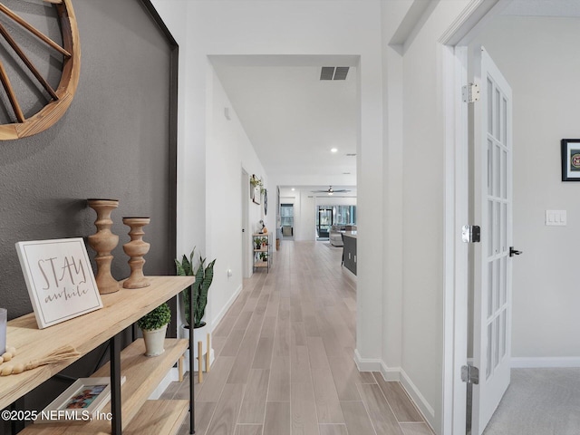 corridor with light wood-type flooring and french doors