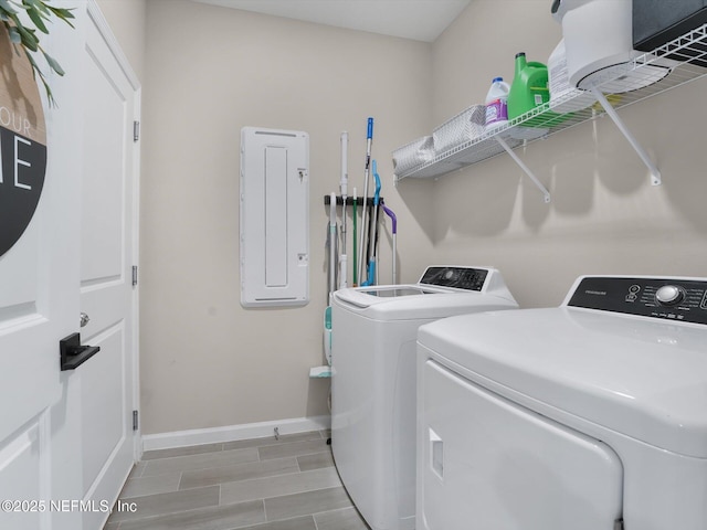 clothes washing area featuring light wood-type flooring, washing machine and dryer, and electric panel