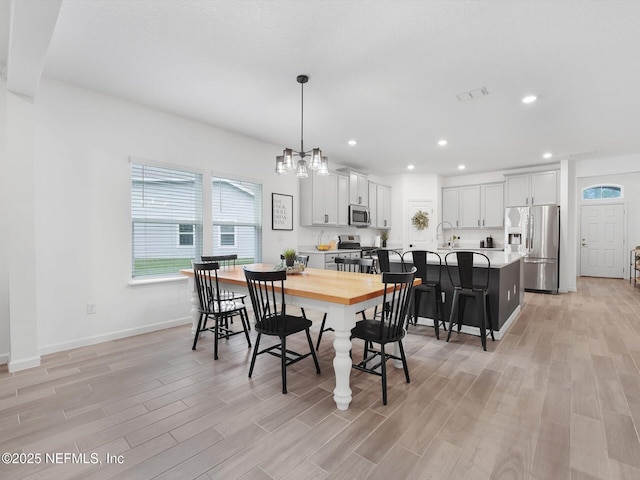 dining area with an inviting chandelier, light hardwood / wood-style flooring, and sink