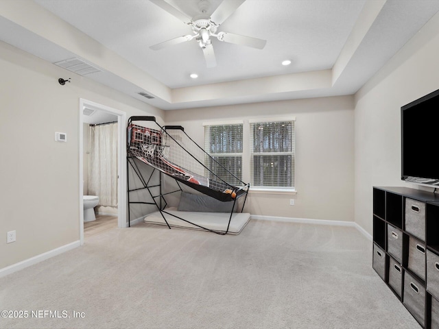 interior space featuring ceiling fan, light colored carpet, and a tray ceiling