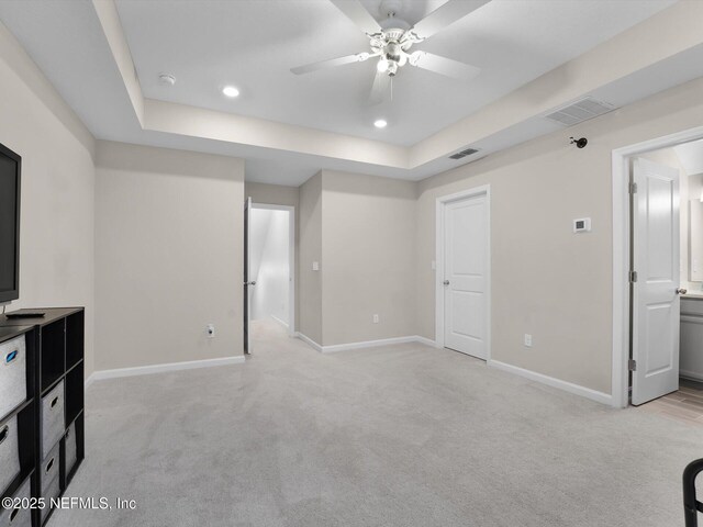 carpeted living room with ceiling fan and a raised ceiling