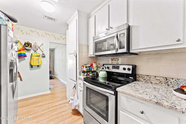 kitchen featuring white cabinets, light stone countertops, stainless steel appliances, and tasteful backsplash