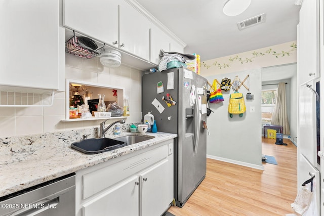 kitchen featuring light wood-type flooring, tasteful backsplash, stainless steel appliances, sink, and white cabinets