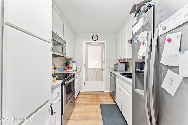 kitchen with light stone countertops, white cabinetry, light wood-type flooring, and appliances with stainless steel finishes