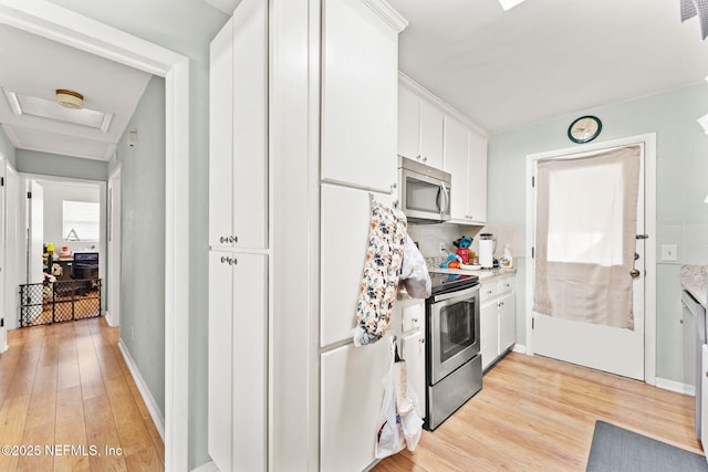 kitchen featuring white cabinetry, backsplash, appliances with stainless steel finishes, and light hardwood / wood-style flooring