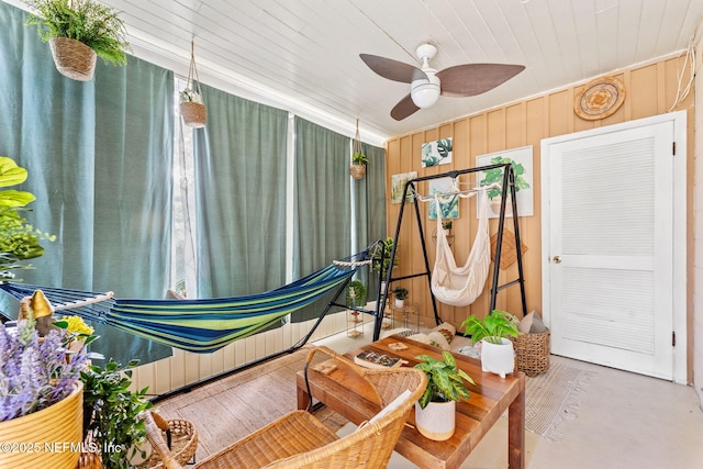 sitting room with wood walls, ceiling fan, and wooden ceiling