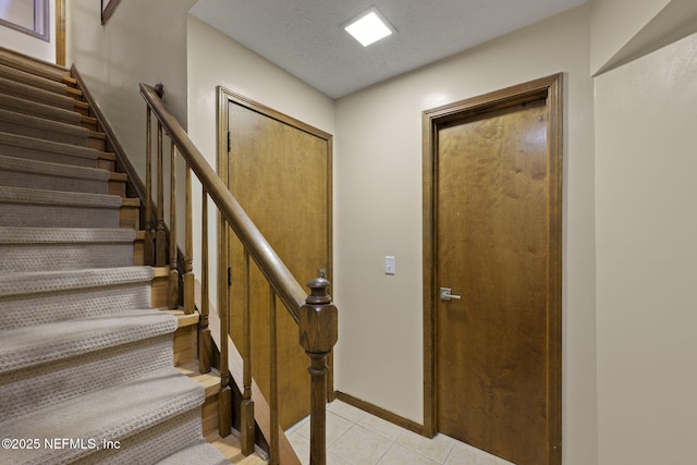 stairs with baseboards, a textured ceiling, and tile patterned floors