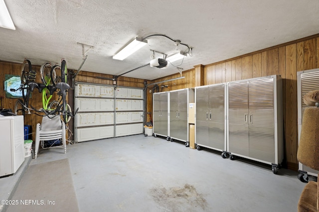 garage with washer / dryer, a garage door opener, and wood walls