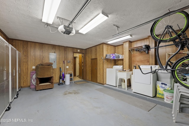 garage with a garage door opener, washing machine and dryer, electric panel, and wooden walls