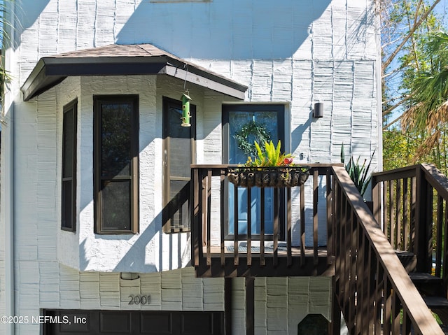 property entrance with a balcony and brick siding