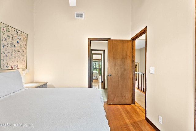 bedroom featuring a high ceiling, visible vents, and light wood-style floors