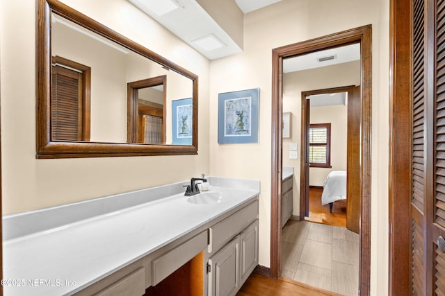 bathroom with ensuite bathroom, wood finished floors, vanity, and visible vents