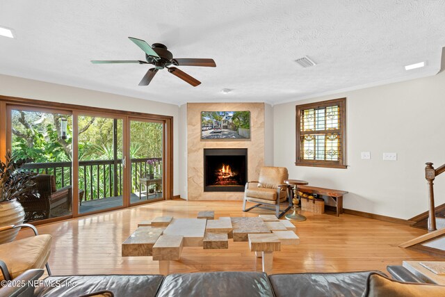 living room featuring a textured ceiling, hardwood / wood-style floors, a high end fireplace, and baseboards