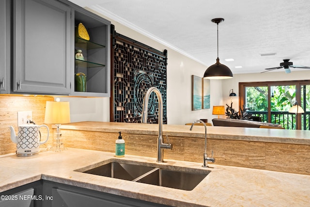 kitchen with pendant lighting, crown molding, gray cabinets, decorative backsplash, and a sink