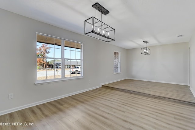 unfurnished dining area with light hardwood / wood-style flooring and a chandelier