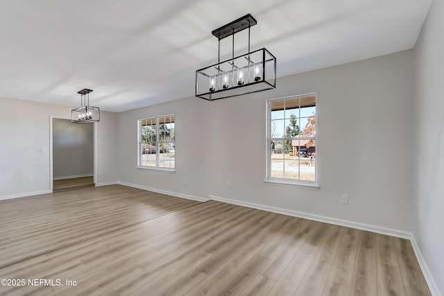 unfurnished dining area featuring plenty of natural light, light hardwood / wood-style floors, and a notable chandelier