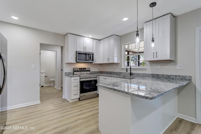 kitchen featuring pendant lighting, white cabinetry, appliances with stainless steel finishes, and sink