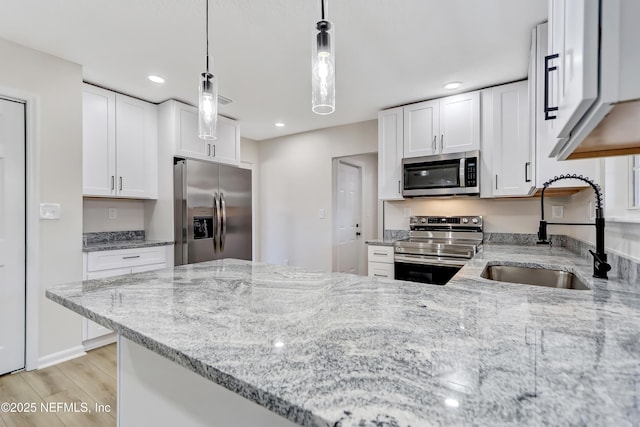 kitchen with white cabinetry, sink, decorative light fixtures, and stainless steel appliances