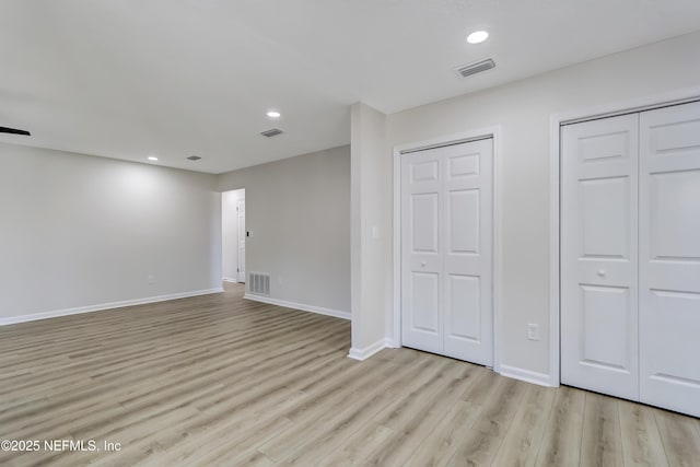 unfurnished bedroom with two closets and light hardwood / wood-style flooring