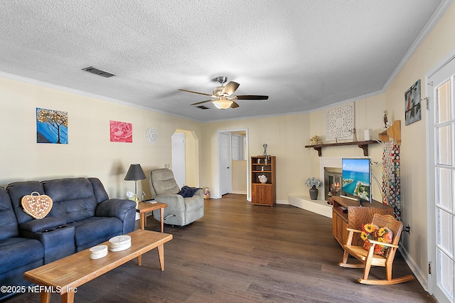 living room featuring crown molding, ceiling fan, dark wood-type flooring, and a textured ceiling