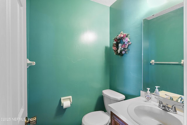 bathroom with a textured ceiling, vanity, and toilet