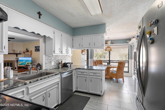 kitchen with kitchen peninsula, appliances with stainless steel finishes, tasteful backsplash, sink, and white cabinetry