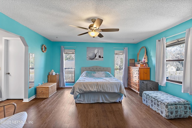 bedroom featuring ceiling fan, dark hardwood / wood-style floors, a textured ceiling, and multiple windows