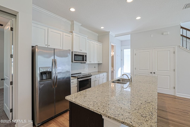 kitchen with appliances with stainless steel finishes, white cabinetry, a kitchen island with sink, and sink