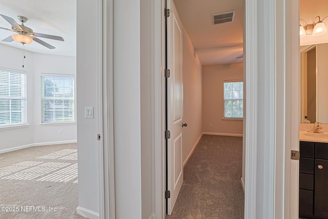 hallway with dark carpet and sink