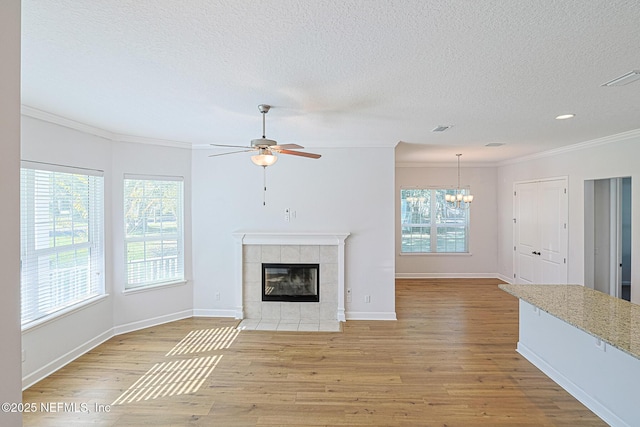 unfurnished living room with a fireplace, light hardwood / wood-style floors, crown molding, and plenty of natural light