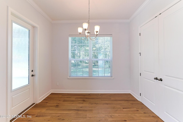 unfurnished dining area with ornamental molding, a chandelier, and wood-type flooring