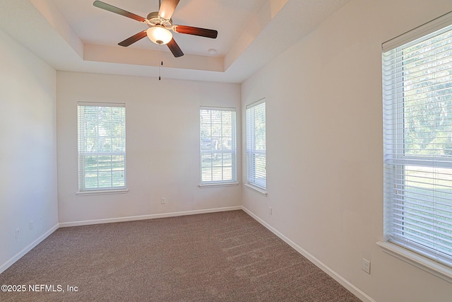 carpeted spare room with ceiling fan and a tray ceiling