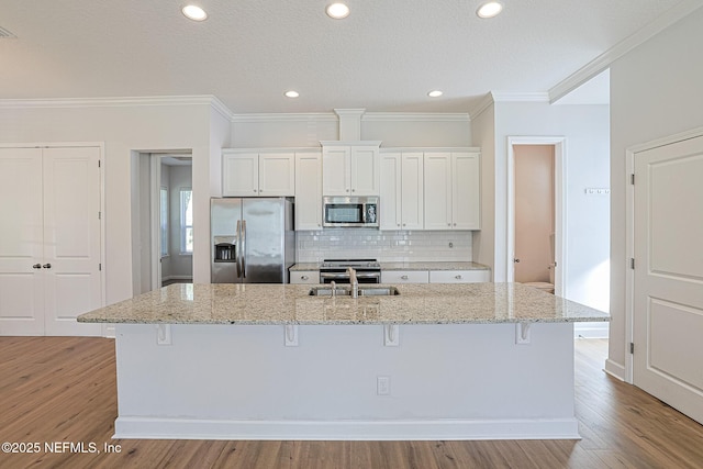 kitchen with stainless steel appliances, white cabinets, and a kitchen island with sink