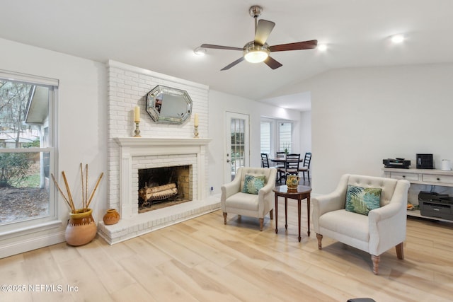 living area with hardwood / wood-style floors, a fireplace, a wealth of natural light, and vaulted ceiling