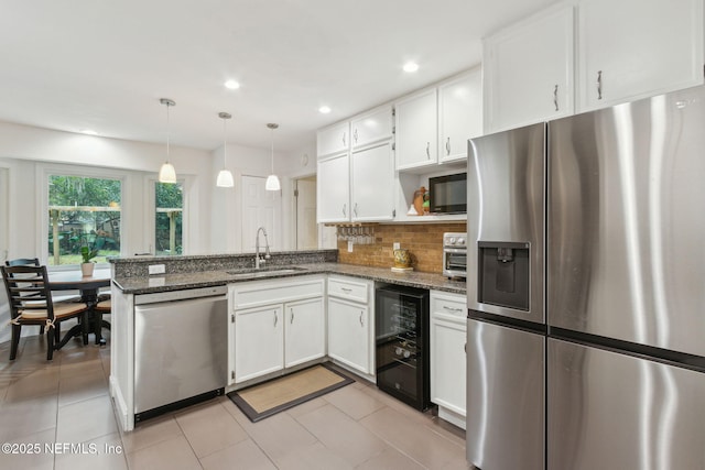 kitchen with sink, white cabinetry, hanging light fixtures, stainless steel appliances, and kitchen peninsula