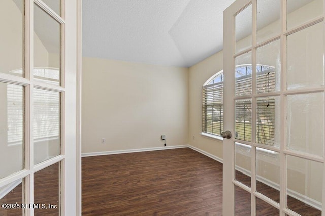 spare room featuring vaulted ceiling and dark hardwood / wood-style flooring