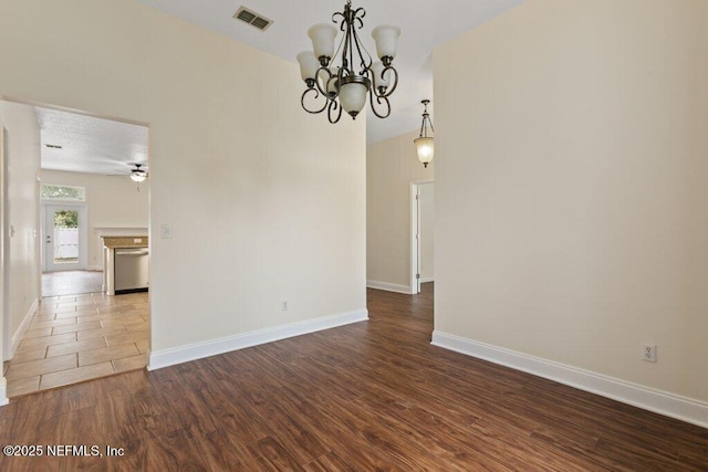 empty room with hardwood / wood-style flooring and ceiling fan with notable chandelier