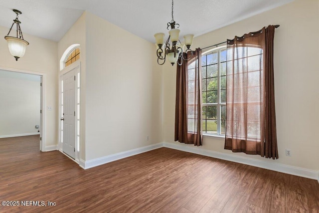 unfurnished dining area with a chandelier and dark hardwood / wood-style flooring